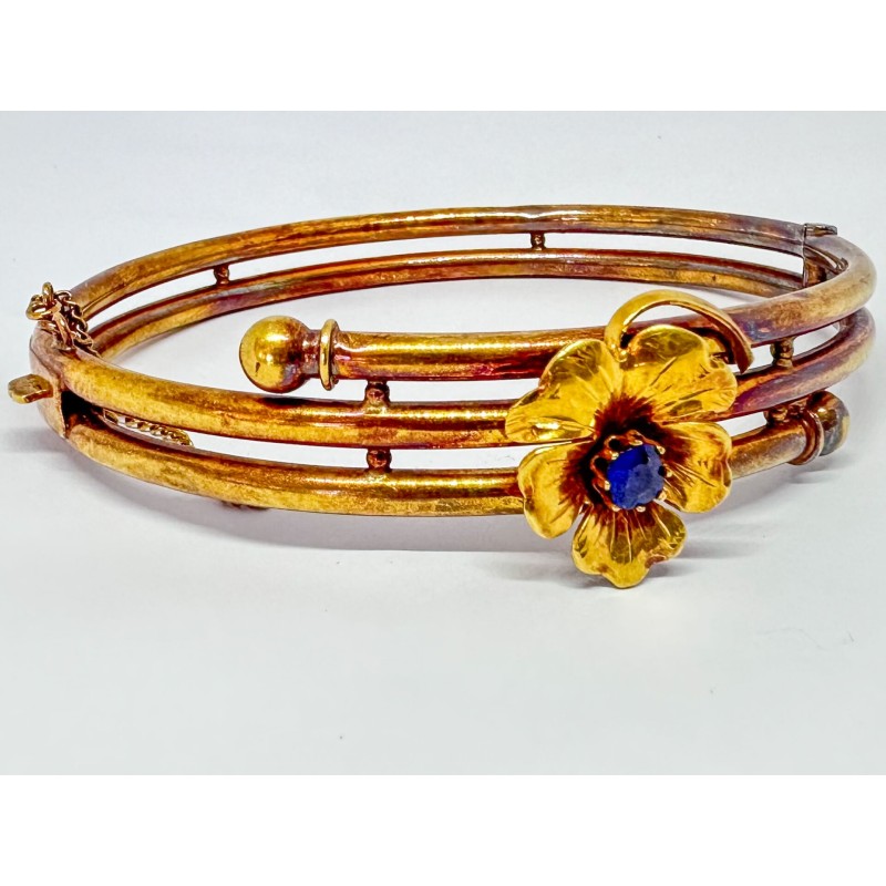 Bracelet rigide en or jaune nuancé 750 millièmes (18K) à enroulement tubulaire. Il est surmonté d'une fleur sertie d'une pierre 