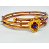 Bracelet rigide en or jaune nuancé 750 millièmes (18K) à enroulement tubulaire. Il est surmonté d'une fleur sertie d'une pierre 