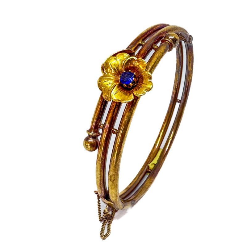 Bracelet rigide en or jaune nuancé 750 millièmes (18K) à enroulement tubulaire. Il est surmonté d'une fleur sertie d'une pierre 